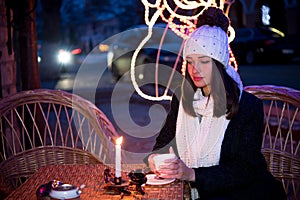 beautiful girl sitting outdoors in winter with a cup and a candle