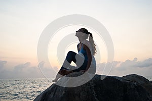 The beautiful girl sitting on stones and looking in a distance, the girl at sunset to meditate in silence, beautiful body. concept