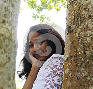 The beautiful girl is sitting under a tree