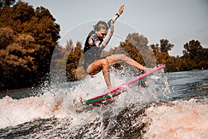 Beautiful girl skillfully jumping over the wave on surf style wakeboard