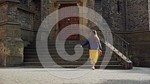 Beautiful girl in skirt spins with happiness in beautiful sunny in background of gothic architecture