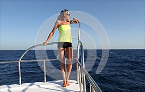 Beautiful girl with slim figure on a yacht in the sea, sea landscape, young cute female model with suntan, blue water view