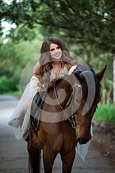 beautiful girl in elegant dress sits on horseback and smiles