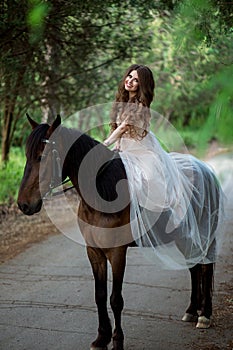 Beautiful girl in a smart dress sits on horseback