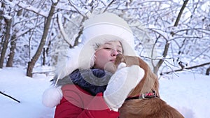Beautiful girl smiles, caresses her beloved dog in winter in park. dog licks girl`s face. girl with hunting dog walks in
