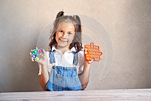 a beautiful girl is smiling holding a pop it hands.