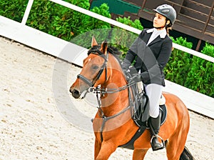 Beautiful girl on sorrel horse in jumping show, equestrian sports.