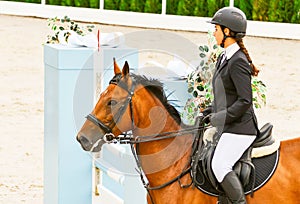 Beautiful girl on sorrel horse in jumping show, equestrian sports.