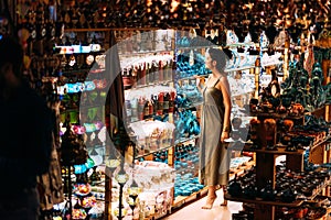 Beautiful girl in a souvenir shop in Morocco. Girl chooses a souvenir Oriental shop. Street shop. Moroccan Souvenirs. Oriental