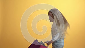 A beautiful girl is spinning in a circle around herself in bags with purchases.