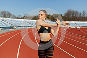 Beautiful girl in sportswear standing on the running track and preparing to run. Morning warm-up before exercise.