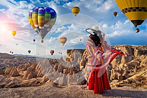 Beautiful girl standing and looking to hot air balloons in Cappadocia, Turkey.