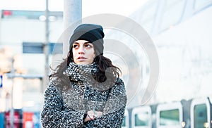 Beautiful girl standing near the railway station trying to hold back her tears - close up front view