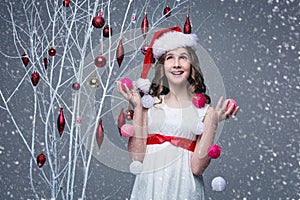 Beautiful girl standing near tree with christmas decorations