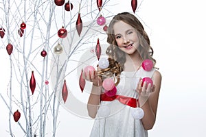 Beautiful girl standing near tree with christmas decorations