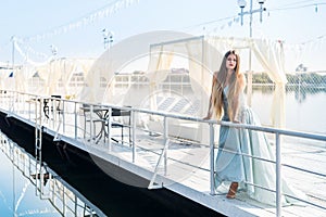 Beautiful girl standing on a pier in amazing mint dress