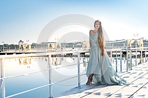 Beautiful girl standing on a pier in amazing mint dress