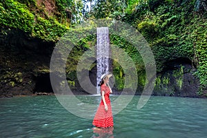 Beautiful girl standing in Tibumana waterfall in Bali, Indonesia.