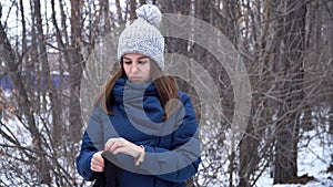 Beautiful girl standing in winter forest and wearing gloves, snowy branches background. Winter forest landscape