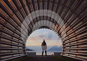 Beautiful girl stands in the arch of the pipe lines