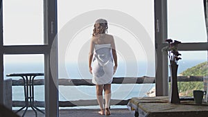 Beautiful girl stands on balcony and looking at sea horizon from luxury terrace.