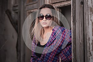 A beautiful girl stands in front of an old wooden window