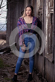 A beautiful girl stands in front of an old wooden window