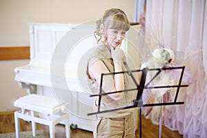 Beautiful girl stands near music stand in room