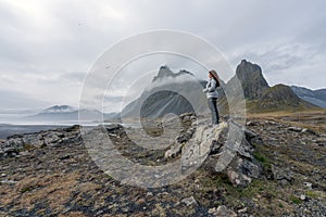 Beautiful Girl stands on a rock looking towards the sea on Hvalnes Peninsula in the southcoast of Iceland. photo