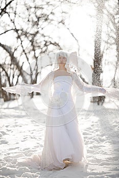 Beautiful girl stands in snowy forest in image of good angel against background of snowfall