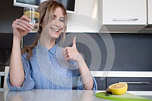 Beautiful girl starts her morning with a glass of water with lemon