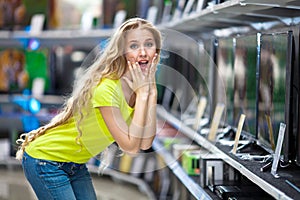 Beautiful girl in the store with TVs wondering prices