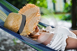 Beautiful girl in a straw hat lies on a hammock