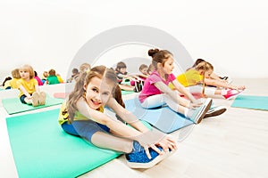 Beautiful girl stretching legs with friends in gym