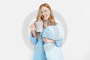 Beautiful girl in striped pajamas, with a Cup in her hands , drinking coffee or tea in the early morning