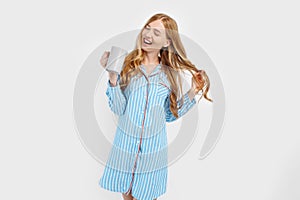 Beautiful girl in striped pajamas, with a Cup in her hands , drinking coffee or tea in the early morning