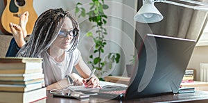 Beautiful girl student is studying at an online lesson at home on a laptop. Concept of distance education and exams