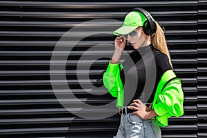 Beautiful girl in stylish sportswear and headphones listens music. Sporty girl in fashion sportswear on the street. Outdoor sports