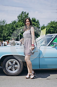 Beautiful girl on a summer sunny day near a muscle car