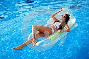 Beautiful girl sunbathing in the pool on an inflatable mattress