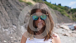 The beautiful girl in sunglasses with reflection of the cameramen on the beach