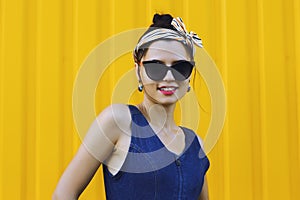 Beautiful girl in sunglasses on a yellow background