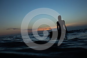 beautiful girl with a surfboard at sunset.