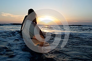 beautiful girl with a surfboard at sunset.