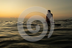 beautiful girl with a surfboard at sunset.