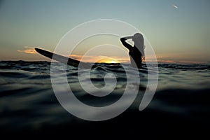 beautiful girl with a surfboard at sunset.