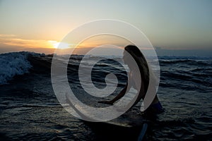 beautiful girl with a surfboard at sunset.