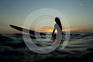 beautiful girl with a surfboard at sunset.