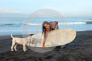 Beautiful Girl. Surfing Woman With Dog And Surfboard On Beach. Smiling Surfer Going To Surf.