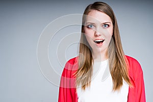 Beautiful girl is surprised by raising eyebrows and opening her mouth looking into the camera photo